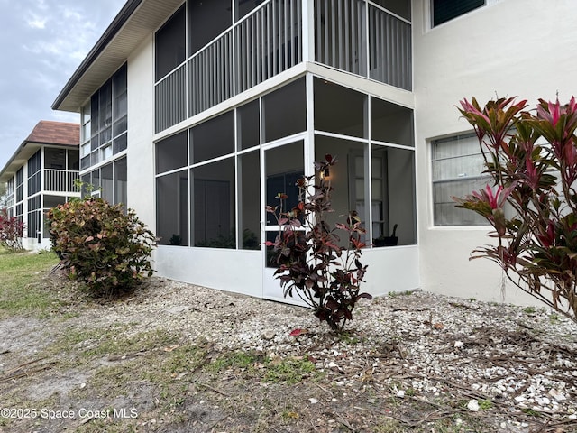 view of side of property featuring stucco siding and a sunroom