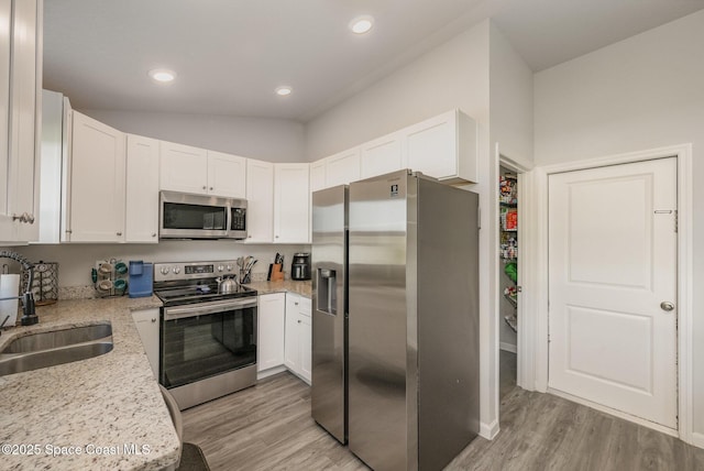 kitchen with white cabinets, appliances with stainless steel finishes, light wood-style floors, and a sink