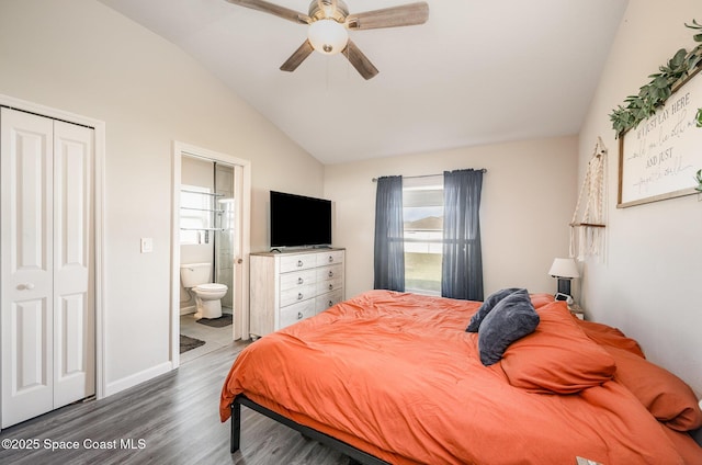 bedroom featuring wood finished floors, baseboards, vaulted ceiling, a closet, and ensuite bathroom