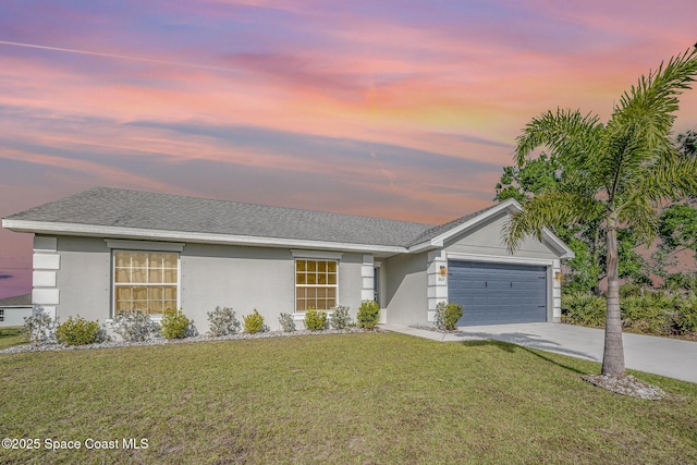 ranch-style house featuring stucco siding, driveway, a yard, roof with shingles, and an attached garage