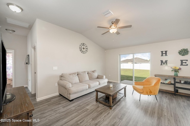 living area featuring visible vents, wood finished floors, baseboards, ceiling fan, and vaulted ceiling