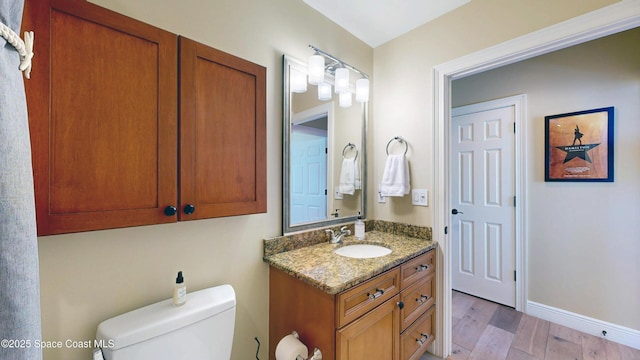 bathroom featuring vanity, toilet, wood finished floors, and baseboards