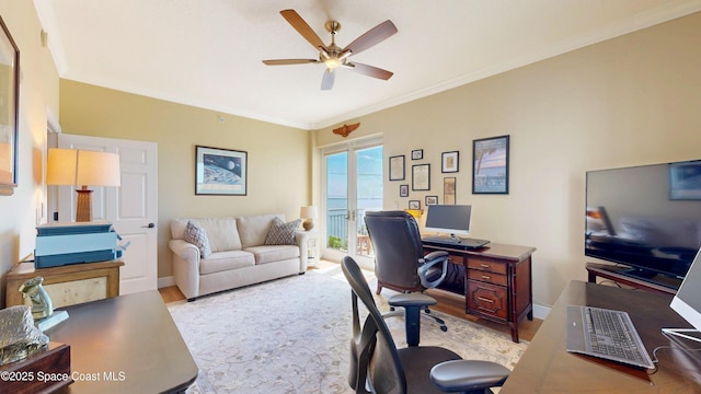 home office with light wood-style floors, baseboards, crown molding, and ceiling fan