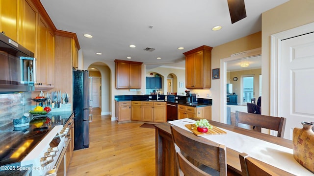 kitchen featuring visible vents, recessed lighting, light wood-style floors, arched walkways, and black appliances