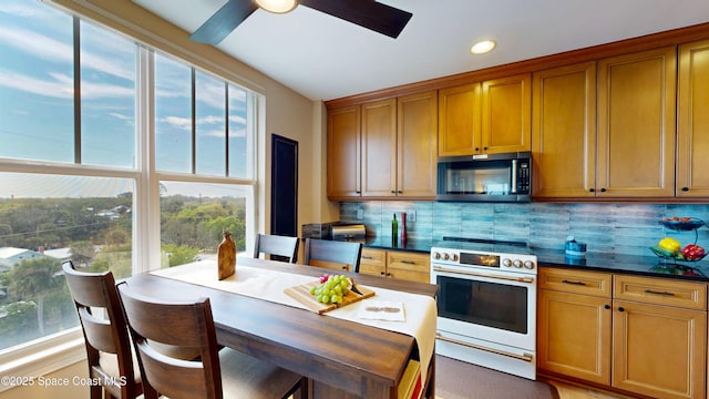 kitchen featuring dark countertops, stainless steel microwave, decorative backsplash, brown cabinetry, and electric range