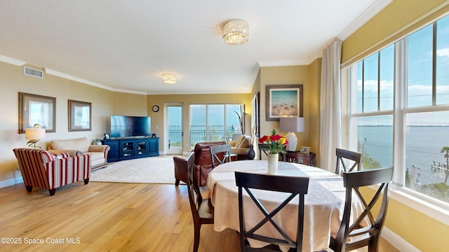 dining room featuring crown molding, baseboards, visible vents, and light wood-type flooring