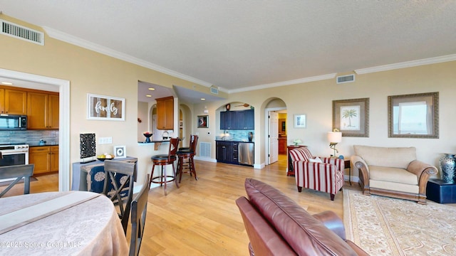 living area with arched walkways, visible vents, and light wood finished floors