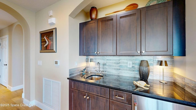 bar featuring indoor wet bar, visible vents, decorative backsplash, and a sink