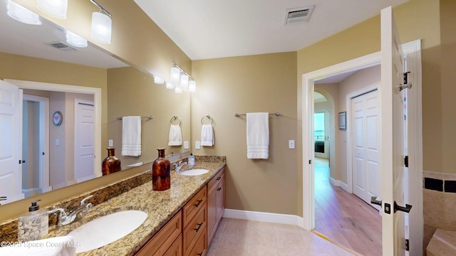 full bath featuring double vanity, baseboards, visible vents, and a sink