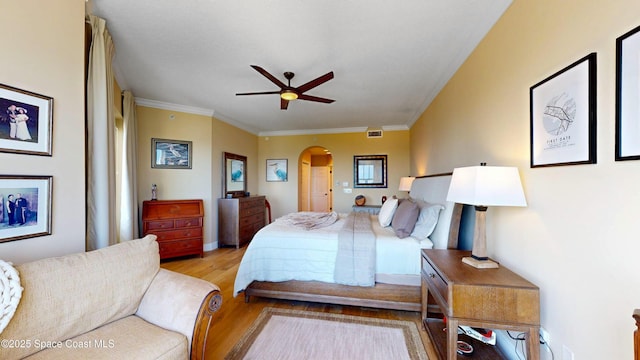 bedroom featuring crown molding, wood finished floors, arched walkways, and visible vents