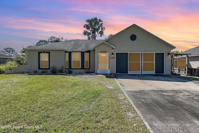 single story home with stucco siding, driveway, a front lawn, and fence