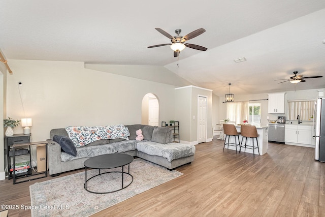 living area with a ceiling fan, lofted ceiling, light wood-style floors, and arched walkways