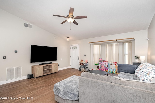 living area with visible vents, lofted ceiling, baseboards, and wood finished floors