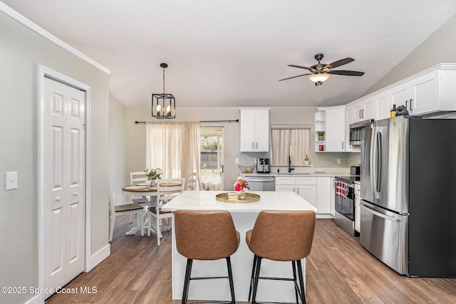 kitchen with a sink, a kitchen island, white cabinetry, and stainless steel appliances