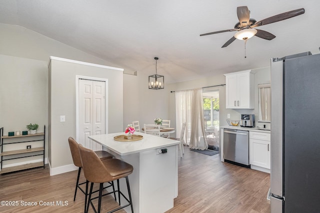 kitchen featuring a kitchen bar, light wood-type flooring, lofted ceiling, appliances with stainless steel finishes, and white cabinetry