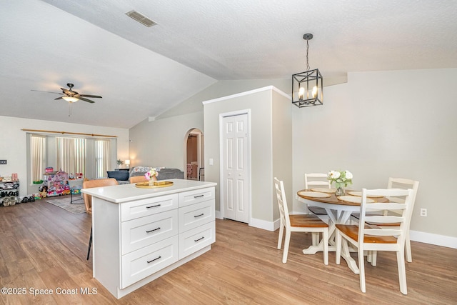 kitchen featuring arched walkways, visible vents, light wood finished floors, and white cabinetry