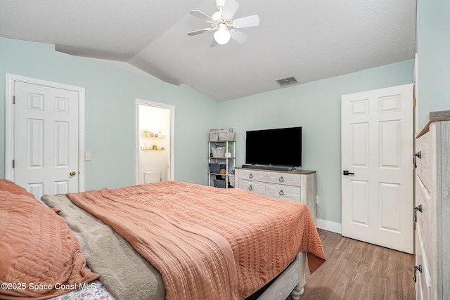 bedroom with visible vents, light wood-style flooring, a textured ceiling, ceiling fan, and vaulted ceiling