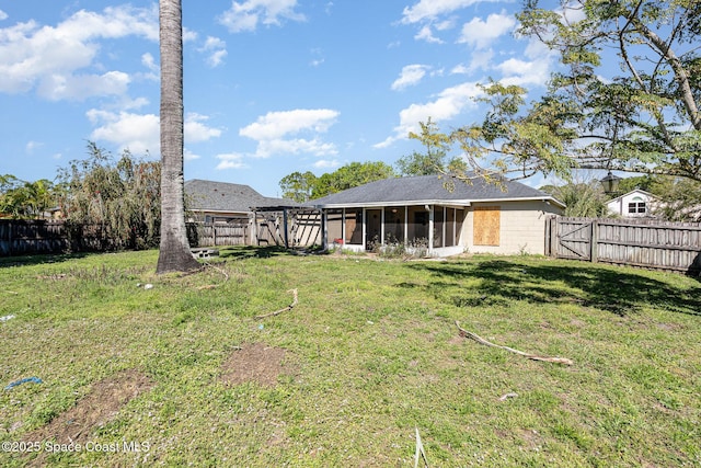 view of yard featuring a gate, a fenced backyard, and a sunroom