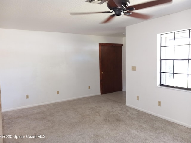 carpeted spare room featuring baseboards and a ceiling fan