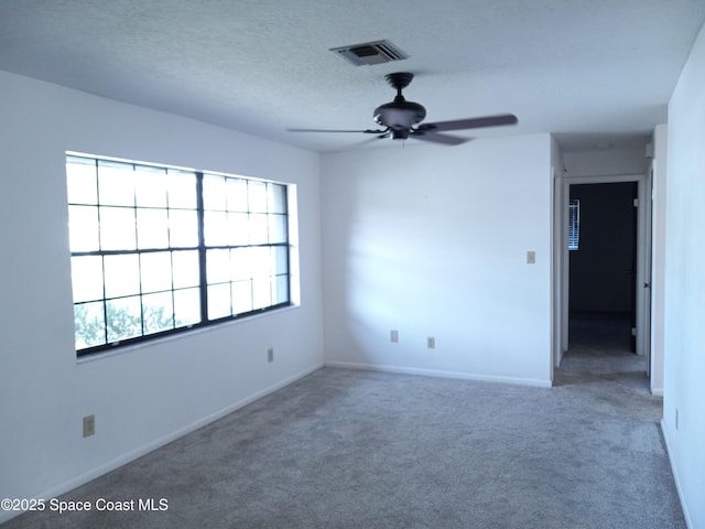 empty room with baseboards, visible vents, carpet floors, ceiling fan, and a textured ceiling