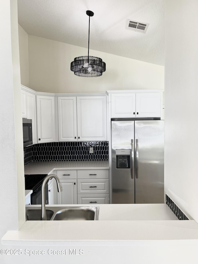 kitchen with a sink, visible vents, stainless steel fridge, and white cabinets