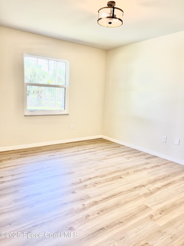 spare room featuring baseboards and wood finished floors