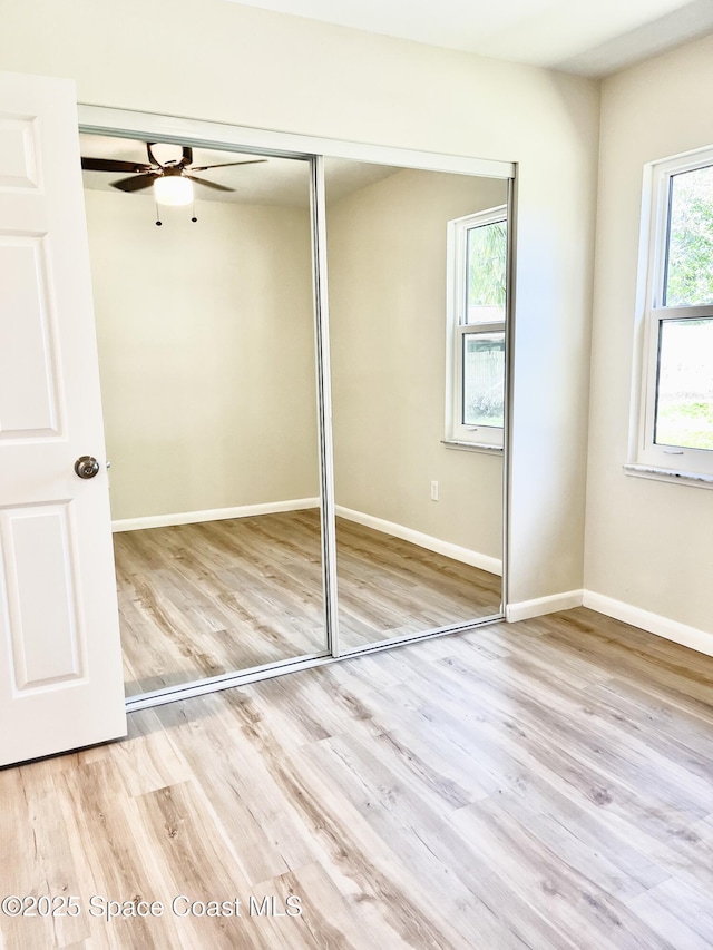 interior space featuring a closet, light wood-style flooring, and baseboards