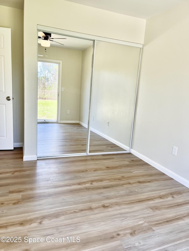 unfurnished bedroom featuring a closet, baseboards, and wood finished floors