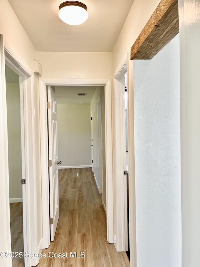 corridor with visible vents, baseboards, and light wood-style flooring