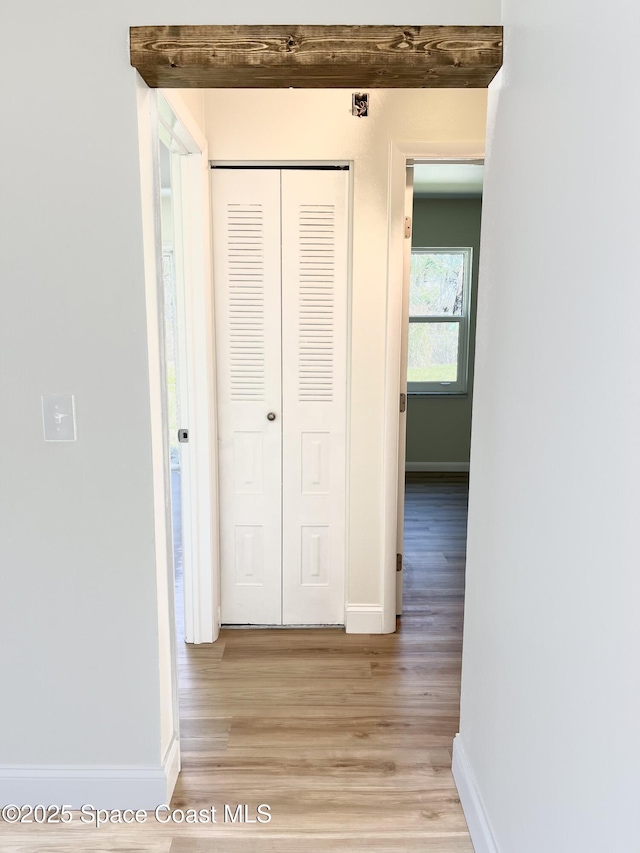 hall featuring light wood-type flooring and baseboards