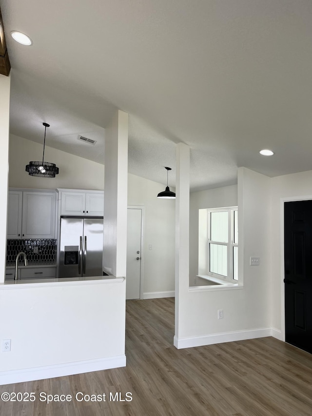 kitchen with visible vents, wood finished floors, stainless steel fridge with ice dispenser, decorative backsplash, and lofted ceiling