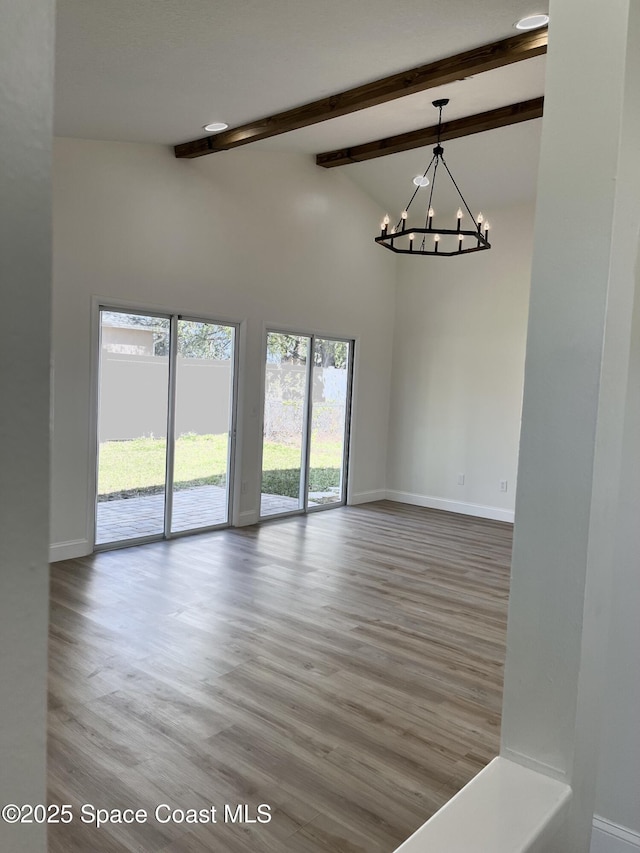 unfurnished room with baseboards, beamed ceiling, wood finished floors, a notable chandelier, and high vaulted ceiling