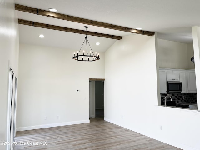 unfurnished dining area with light wood finished floors, baseboards, beamed ceiling, recessed lighting, and a notable chandelier