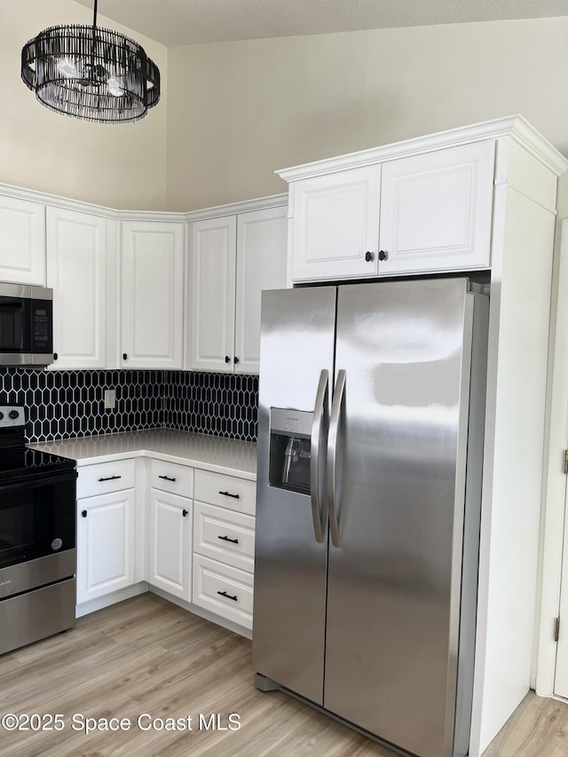 kitchen with stainless steel appliances, light wood-style floors, white cabinets, and light countertops