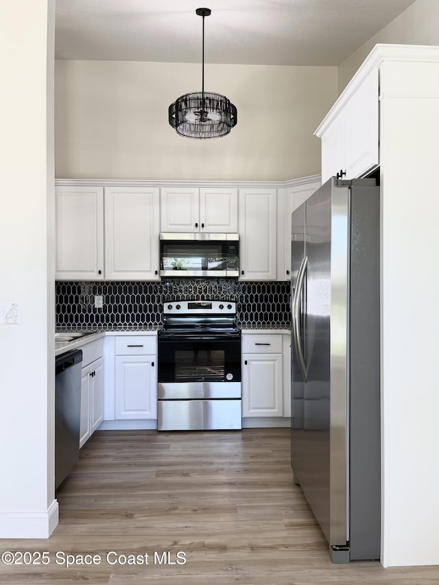 kitchen featuring pendant lighting, backsplash, appliances with stainless steel finishes, and white cabinets