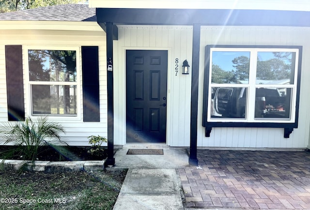 view of exterior entry with a shingled roof