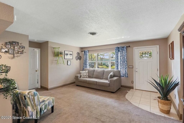 living area featuring light tile patterned floors, baseboards, visible vents, a textured ceiling, and light carpet