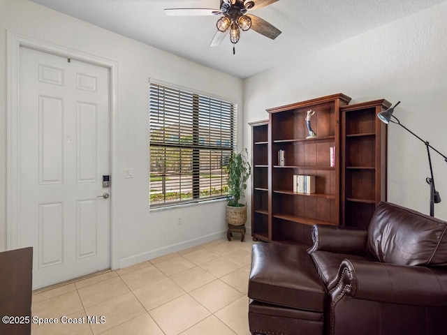 sitting room with light tile patterned flooring, baseboards, and a ceiling fan