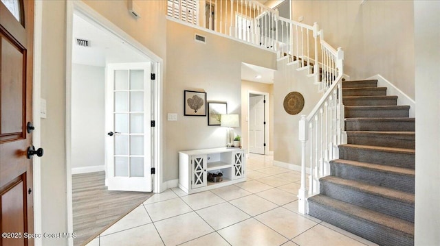 stairway with tile patterned flooring, a high ceiling, baseboards, and visible vents