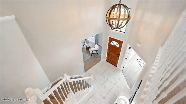 foyer with light tile patterned floors, baseboards, an inviting chandelier, and a towering ceiling