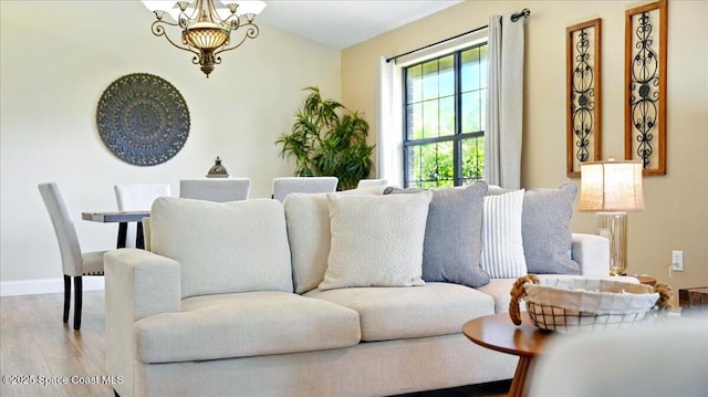 living room with radiator heating unit, wood finished floors, baseboards, and a chandelier