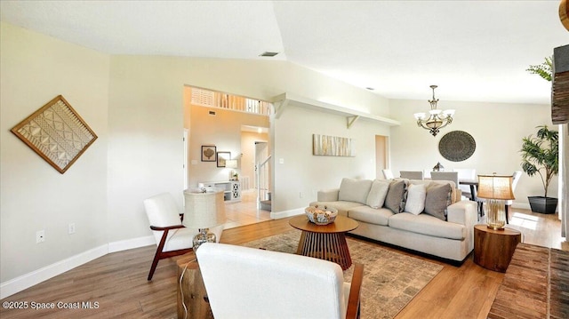 living room with baseboards, lofted ceiling, an inviting chandelier, and wood finished floors