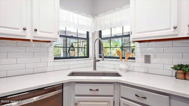 kitchen with white cabinets, dishwasher, light countertops, and a sink