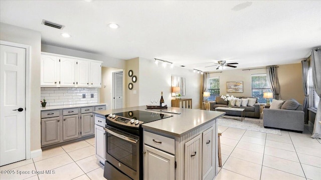 kitchen featuring visible vents, backsplash, ceiling fan, light tile patterned floors, and stainless steel range with electric cooktop