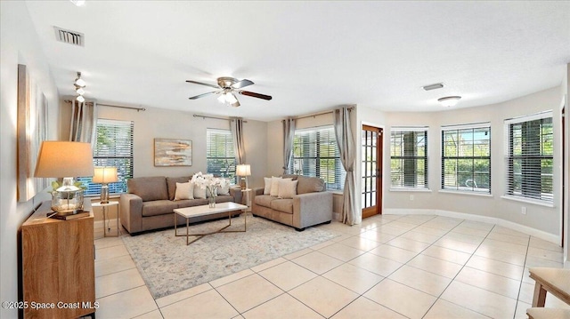 living room featuring light tile patterned flooring, visible vents, baseboards, and a ceiling fan