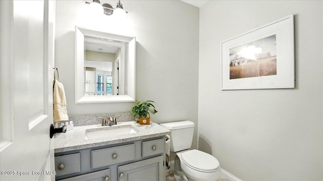 bathroom with baseboards, toilet, and vanity