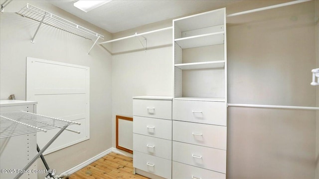 walk in closet with light wood-style floors