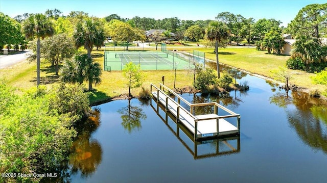 view of dock featuring a water view, a lawn, and fence