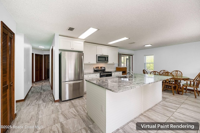 kitchen featuring a kitchen island with sink, light stone counters, stainless steel appliances, white cabinetry, and visible vents