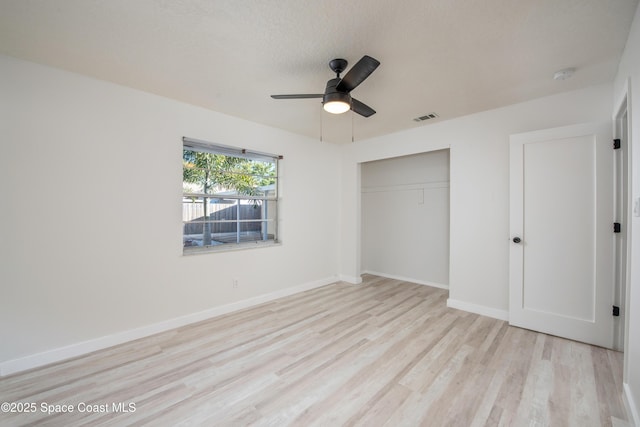 unfurnished bedroom featuring visible vents, baseboards, wood finished floors, a closet, and a ceiling fan